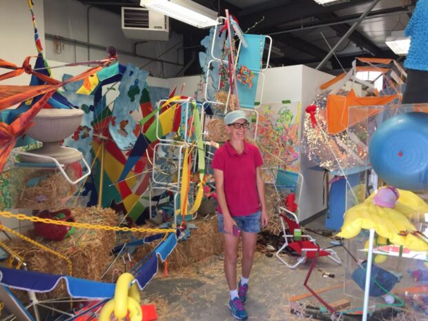 image of artist Brianna Rigg standing in front of colorful objects